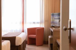 a hotel room with a bed and a chair and a television at NilHotel Florence in Florence