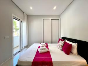 Un dormitorio con una cama grande con almohadas rojas y blancas. en Praia da Rocha Modern by Homing, en Portimão