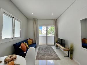 Una sala de estar con un sofá azul y un televisor. en Praia da Rocha Modern by Homing, en Portimão
