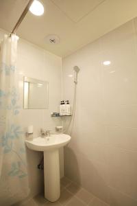 Baño blanco con lavabo y espejo en Stay RomanticTrip_Hostel en Gyeongju