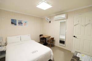 a bedroom with a white bed and a table and a door at Stay RomanticTrip_Hostel in Gyeongju