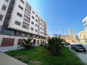 a building with two palm trees next to a street at Appartement Nador Al Jadid Wifi Free in Nador