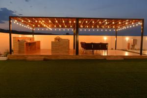 a pavilion with lights and a table and chairs at استراحة المرجانalmarjan chalet in Ḑibāb