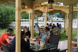 un grupo de personas sentadas en una mesa bajo un cenador en Raku Guest house, en Leh