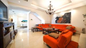 Luxury Villa Allure في Dhafnés: غرفة معيشة مع أريكة برتقالية وطاولة