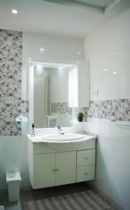 a white bathroom with a sink and a mirror at Appartement confortable proche plage et centre ville in Nabeul