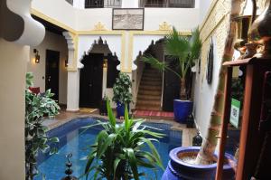 una casa con piscina y plantas frente a ella en Riad des Etoiles, en Marrakech