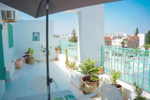 a balcony with potted plants and an umbrella at Appartement confortable proche plage et centre ville in Nabeul