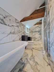 een badkamer met een wit bad en een toilet bij Bainvalley Cottages - Group Accommodation in Lincolnshire