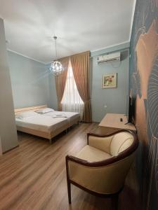 a bedroom with a bed and a chair and a couch at Гостиница Amulet in Taraz