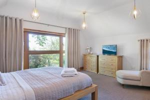 a bedroom with a bed and a window and a chair at The Roost Group - The Coach House - HOT TUB in Gravesend