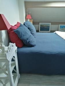 um quarto com uma cama com lençóis azuis e almofadas vermelhas em Chambres d'hôtes le Clos de la Presle, Compostelle em Saint-Georges-Haute-Ville