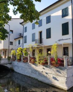 a building next to a river with potted plants at Break Affittacamere in San Vito al Tagliamento