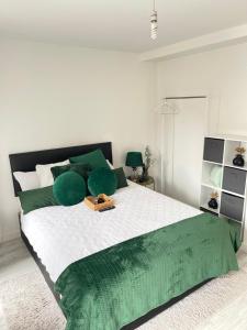 a white bedroom with a large bed with green pillows at Cosy Bedrooms in Manchester