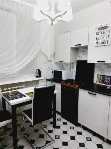 a kitchen with white cabinets and a table with a chair at Квартира in Bender