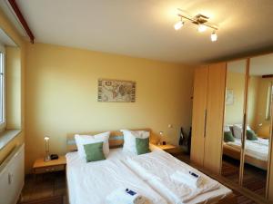 een slaapkamer met een bed met witte lakens en een spiegel bij Meer, Whg 15 in Zingst