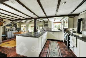 a large kitchen with white cabinets and a large island at Powis House East Cottage in Stirling