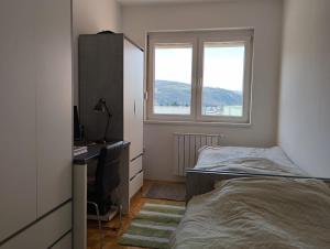 1 dormitorio con cama, escritorio y ventana en Azure apartments en Ilijaš