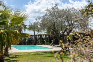 a swimming pool in a yard with a bench and trees at Casa Il Geranio in Piedimonte Etneo