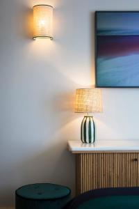 une table avec une lampe et un tabouret à côté d'un mur dans l'établissement Hôtel Le Café de Paris, à Biarritz