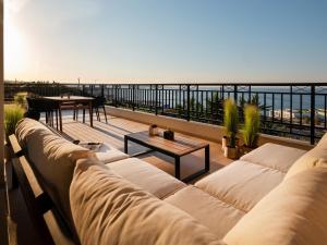 a living room with a couch and a table on a balcony at Zuzu Riviera Living in Hersonissos