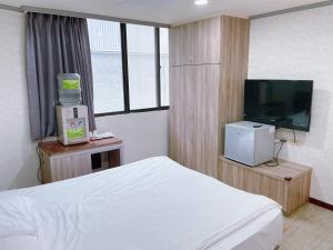 a bedroom with a bed and a flat screen tv at A22 Wei Lu Hotel in Zhongli