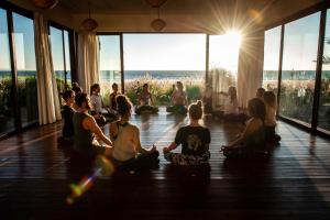 un grupo de personas sentadas en una clase de yoga en Paradis Plage Surf Yoga & Spa en Taghazout