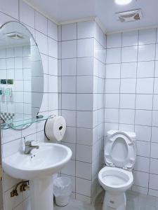 a bathroom with a sink and a toilet and a mirror at A22 Wei Lu Hotel in Zhongli