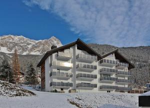 a large apartment building in the snow with mountains at Tgesa La Niva 11 in Savognin