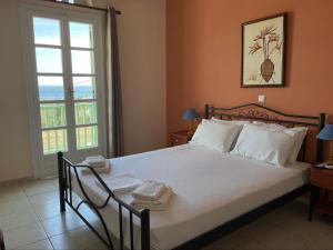 um quarto com uma grande cama branca e uma janela em Kyklades em Agios Loannis