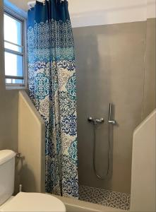 a bathroom with a shower with a blue and white shower curtain at Kyklades in Agios Ioannis