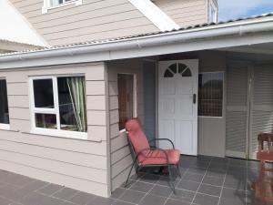 a red chair sitting on the side of a house at Granny flat in Seafield