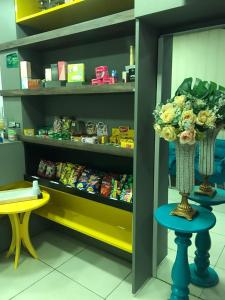 a store aisle with a vase of flowers on a stool at Lax Hotel acesso através de escadas in Campina Grande