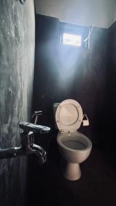 a bathroom with a toilet in a dark room at Rustique House dbl in Nuwara Eliya