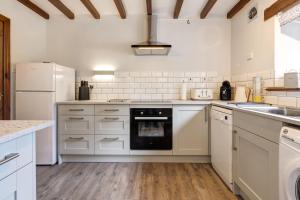 a kitchen with white cabinets and a black oven at Manor Farm Barn Cottage in Burton