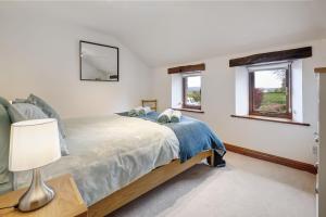 a bedroom with a bed and two windows at Manor Farm Barn Cottage in Burton