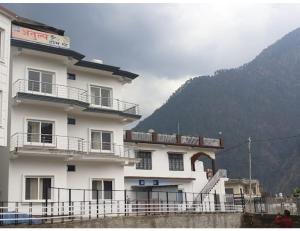 un gran edificio blanco con balcones y una montaña en Atulya Home Stay, Uttarkashi, en Dharāsu