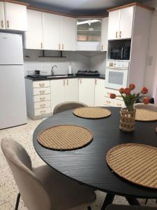 a kitchen with a table and chairs and a kitchen with white cabinets at LTD Hadas Garden apartment in Tiberias