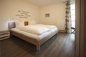 Schlafzimmer mit einem Bett mit weißer Bettwäsche und Holzböden in der Unterkunft Residenz am Balmer See - BS 11 mit Wellnessbereich in Balm