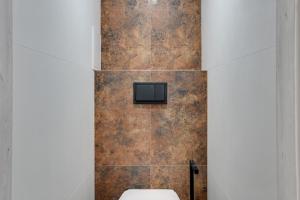 a bathroom with a toilet and a tiled wall at Platinium Apartament Morski in Gdańsk