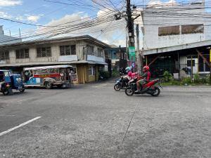 dos personas van en motocicleta por una calle de la ciudad en 5J’s Space Rental, en Legazpi