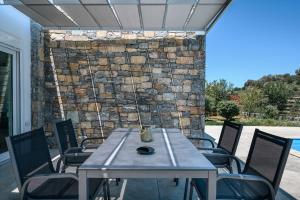 einen Tisch und Stühle auf einer Terrasse mit einer Steinmauer in der Unterkunft Kalostous in Agia Triada