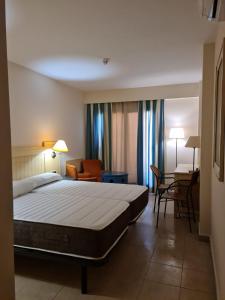 イスラ・カネラにあるJardines de isla canela Punta del moralのベッド、テーブル、椅子が備わるホテルルームです。