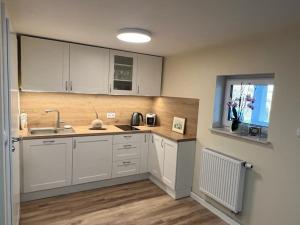 a kitchen with white cabinets and a sink and a window at Winnica pod Skrzydłami in Santok