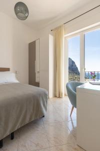 una camera con un letto e una sedia e una finestra di Albergo La Prora a Capri