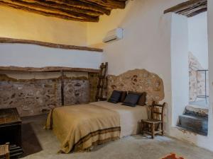 1 dormitorio con cama y pared de piedra en Cas Orvais con piscina y jardín en Sant Jordi