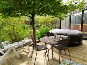 eine Terrasse mit einem Tisch, Stühlen und einem Baum in der Unterkunft chambres d'hôtes naturistes de la moque souris in Saint-Pierre-de-Mailloc