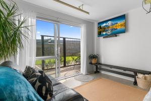 a living room with a couch and a large window at Marram Studio - Mangawhai Holiday Studio in Mangawhai