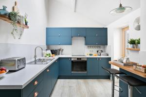 a kitchen with blue cabinets and a sink at Cockington Cottages in Torquay