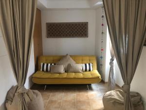 um sofá amarelo numa sala de estar com cortinas em La petite maison em Portimão